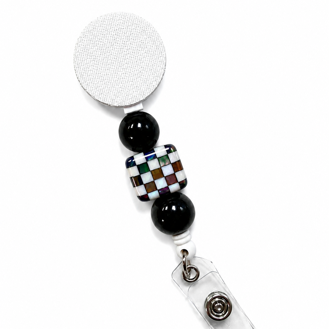 Iridescent checkerboard badge reel featuring a multicolor mosaic checkerboard bead with glossy black decorative beads on a white retractable badge reel. Stylish interchangeable beaded work badge accessory.