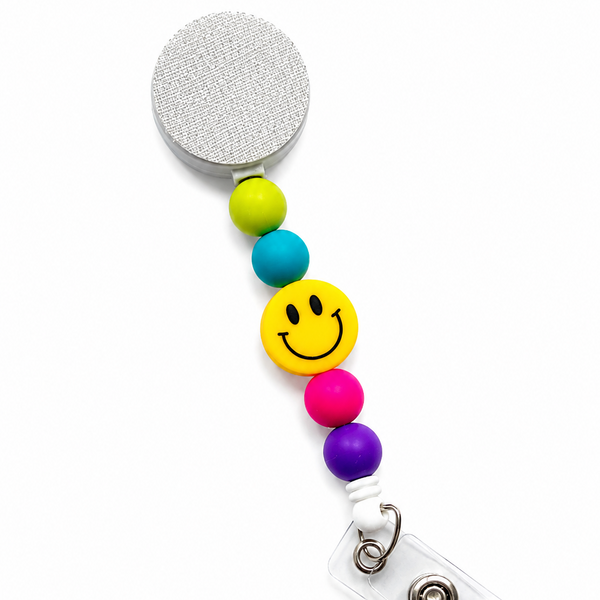 Yellow Smiley Face badge reel featuring a cheerful yellow happy face design with lime green, turquoise blue, hot pink, and purple decorative beads, retractable badge reel functionality, and secure badge holder attachment.